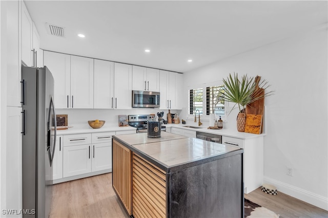 kitchen featuring white cabinetry, a center island, sink, and stainless steel appliances