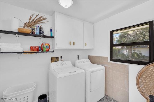 washroom featuring cabinets, tile walls, and independent washer and dryer