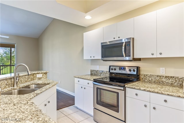 kitchen featuring stainless steel appliances, lofted ceiling, sink, white cabinetry, and light wood-type flooring