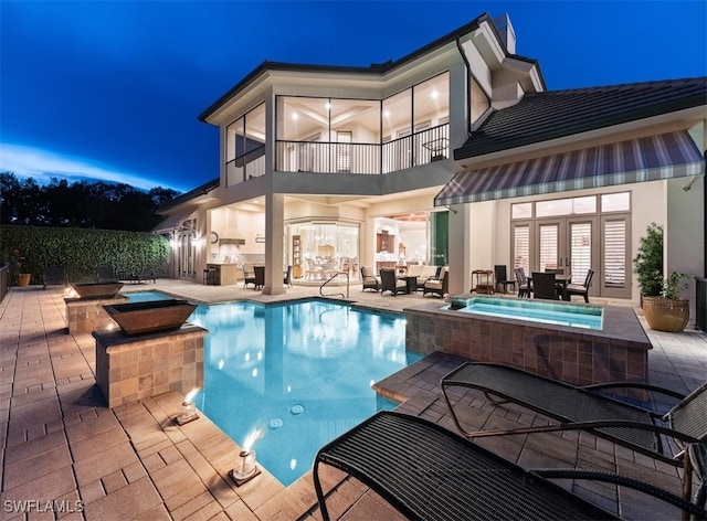 pool at twilight featuring a patio area, an in ground hot tub, and an outdoor kitchen