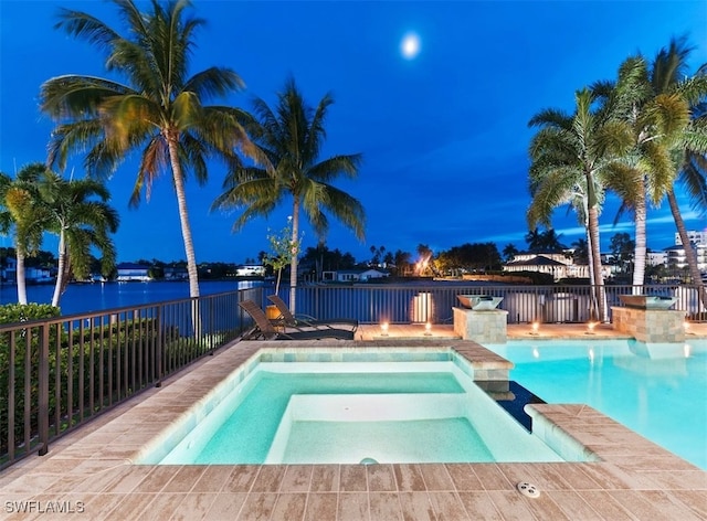 view of swimming pool with a water view and an in ground hot tub