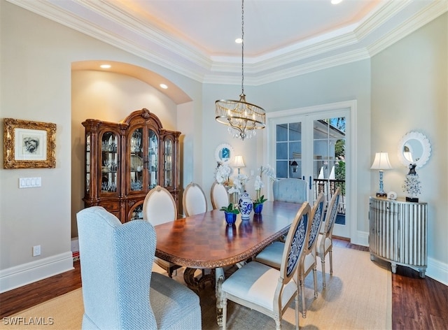 dining space featuring wood-type flooring, crown molding, a tray ceiling, and an inviting chandelier