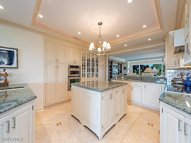 kitchen featuring double oven, a tray ceiling, a center island, and hanging light fixtures