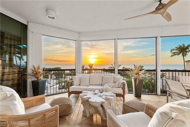 sunroom / solarium with ceiling fan and a water view