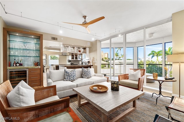 sunroom featuring plenty of natural light, ceiling fan, beverage cooler, and bar area