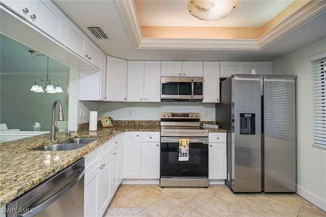 kitchen with dark stone counters, stainless steel appliances, white cabinets, and a raised ceiling