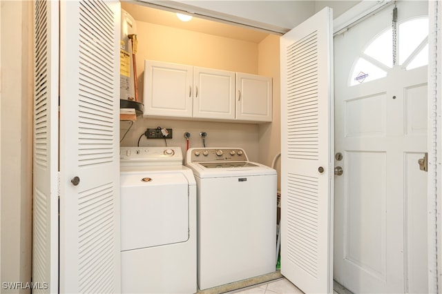 washroom with light tile patterned floors, cabinets, and washer and dryer