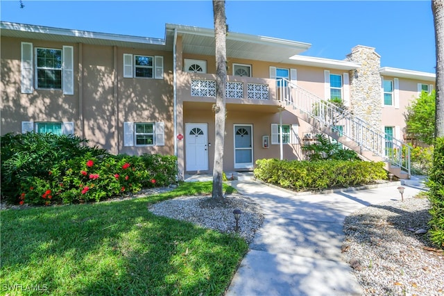 multi unit property with a balcony and a front lawn