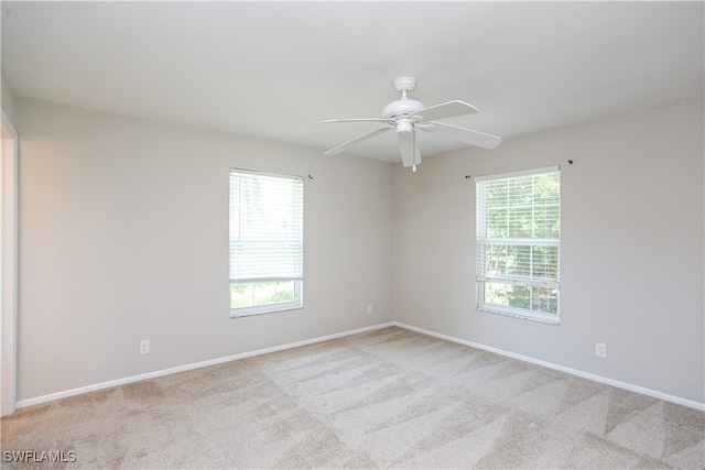 carpeted empty room featuring ceiling fan and a wealth of natural light