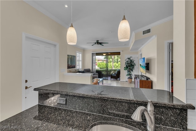 kitchen with ceiling fan, decorative light fixtures, sink, and dark stone counters