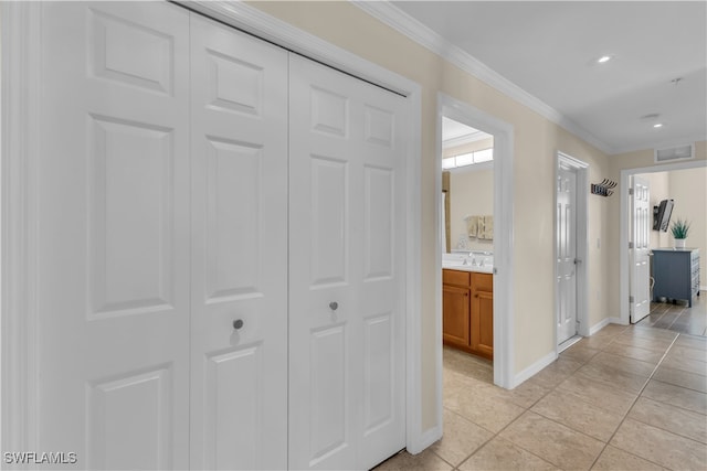 hall featuring crown molding, sink, and light tile patterned floors