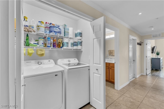 washroom featuring light tile patterned floors, ornamental molding, and washer and dryer