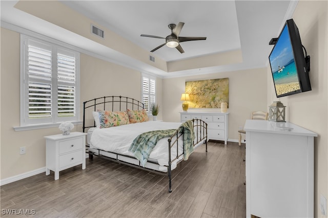 bedroom featuring wood-type flooring, a tray ceiling, and ceiling fan