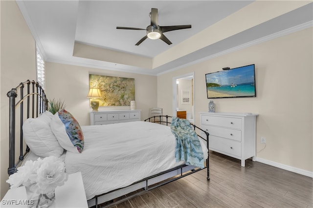 bedroom featuring wood-type flooring, a tray ceiling, ceiling fan, and ornamental molding