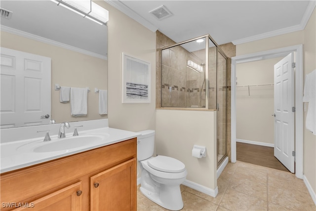 bathroom with ornamental molding, vanity, toilet, and a shower with shower door