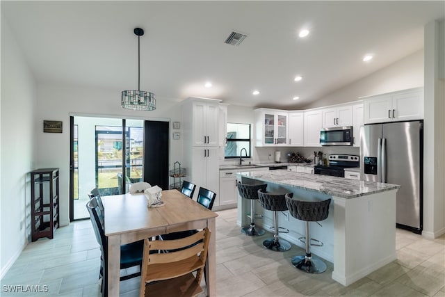 kitchen featuring decorative light fixtures, a center island, stainless steel appliances, and white cabinetry