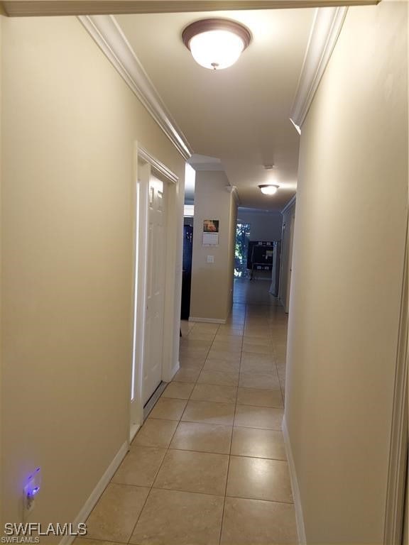 hall with ornamental molding and light tile patterned flooring