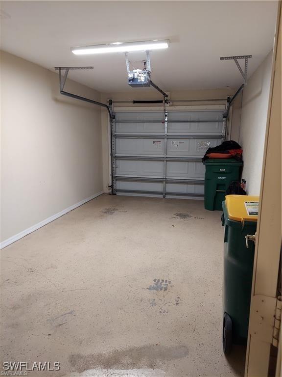 517 Robin Hood Cir Unit 102, Naples, FL 34104 - garage featuring a garage door opener and baseboards