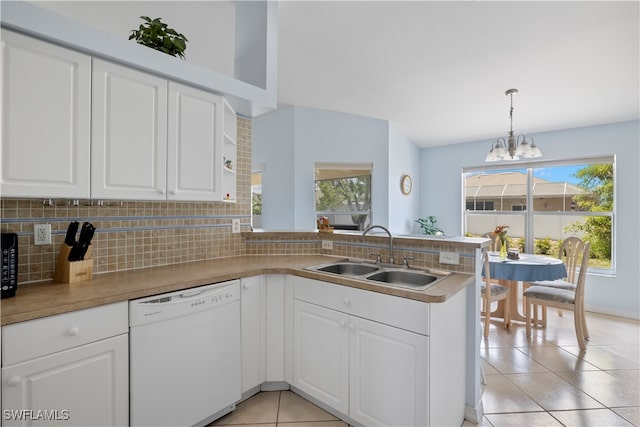 kitchen featuring kitchen peninsula, light tile patterned floors, pendant lighting, white dishwasher, and sink