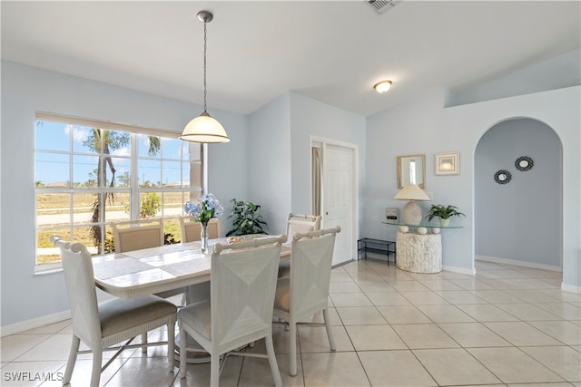 tiled dining area with lofted ceiling and a healthy amount of sunlight