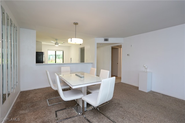 carpeted dining area with ceiling fan