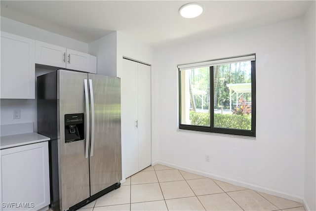 kitchen featuring white cabinetry, light tile patterned floors, and stainless steel fridge