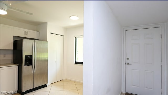 kitchen with stainless steel fridge, white cabinetry, ceiling fan, and light tile patterned floors