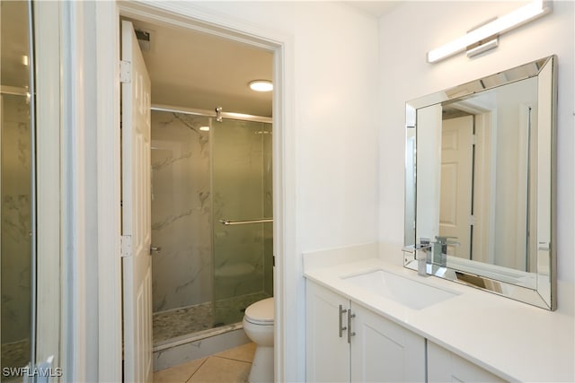 bathroom featuring vanity, toilet, a shower with door, and tile patterned floors