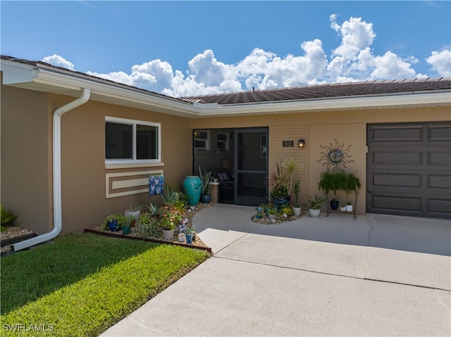 view of exterior entry featuring a lawn and a garage