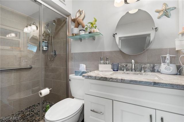 bathroom featuring toilet, tile walls, decorative backsplash, vanity, and walk in shower