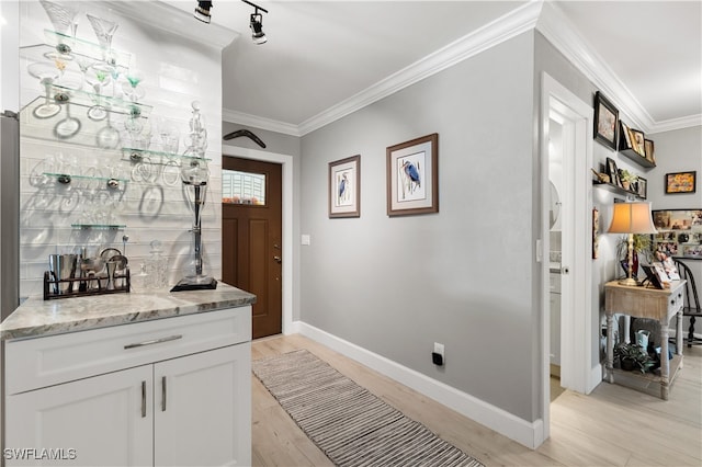 interior space with white cabinetry, light wood-type flooring, light stone counters, and crown molding