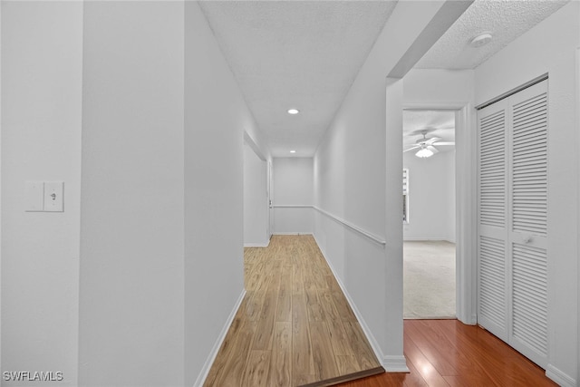 hall with a textured ceiling and wood-type flooring