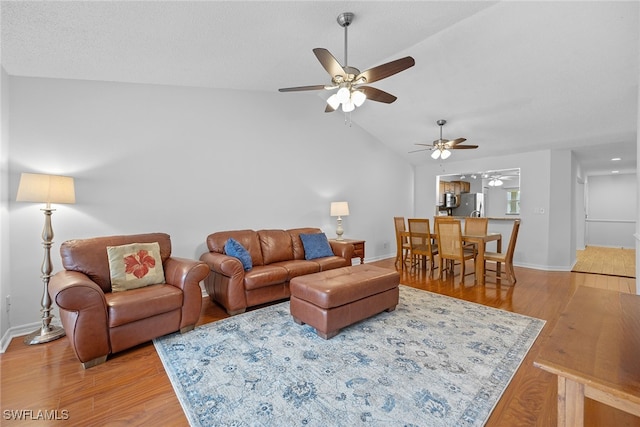 living room with ceiling fan, lofted ceiling, and light hardwood / wood-style floors