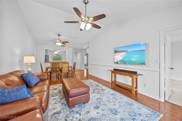 living room featuring wood-type flooring, lofted ceiling, and ceiling fan