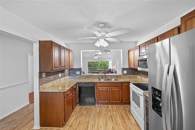 kitchen featuring light hardwood / wood-style floors, sink, appliances with stainless steel finishes, light stone countertops, and ceiling fan