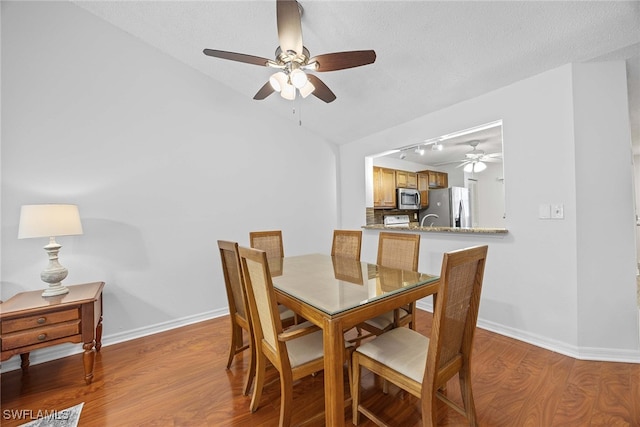 dining room with light wood-type flooring, a textured ceiling, sink, and ceiling fan