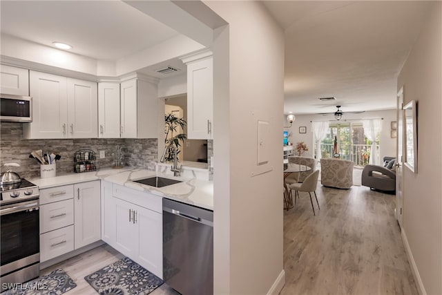 kitchen featuring stainless steel appliances, ceiling fan, sink, and white cabinetry