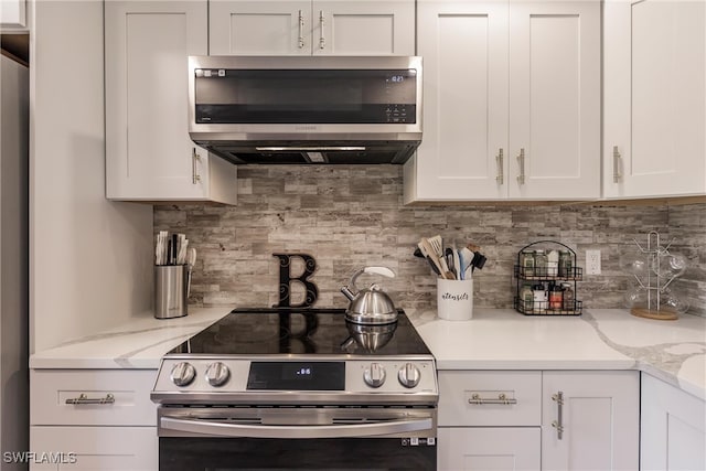 kitchen with decorative backsplash, appliances with stainless steel finishes, light stone counters, and white cabinetry