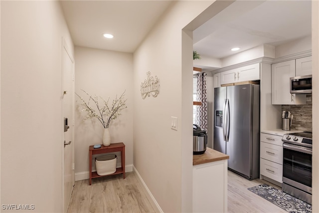 kitchen featuring light wood-type flooring, appliances with stainless steel finishes, butcher block counters, and white cabinetry