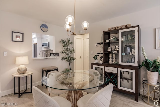 dining space with an inviting chandelier, light wood-type flooring, and sink