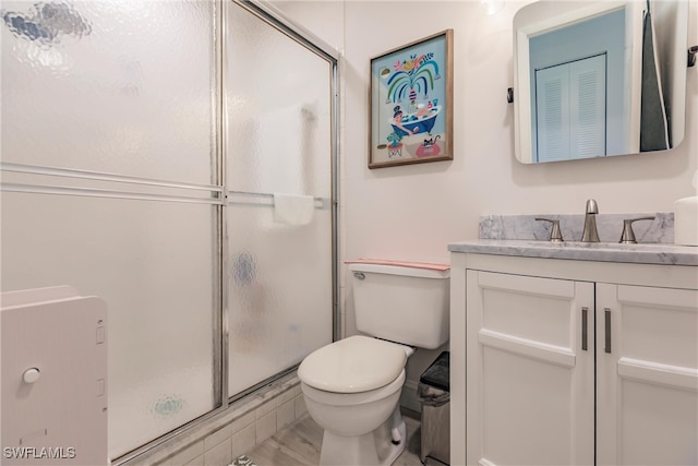 bathroom featuring a shower with shower door, vanity, and toilet