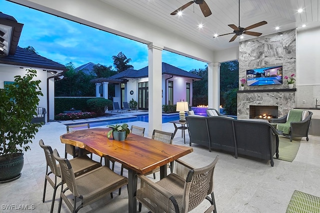 view of patio / terrace with an outdoor living space with a fireplace and ceiling fan