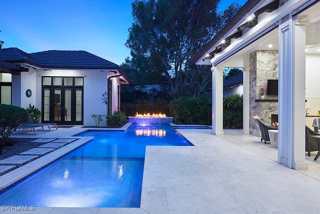 pool at dusk with french doors and a patio