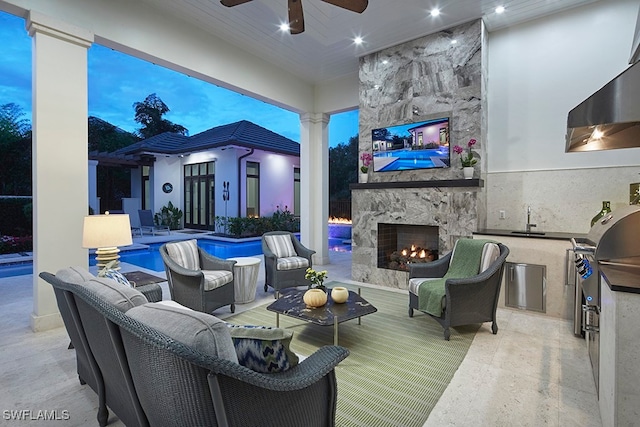 view of patio featuring ceiling fan, sink, and an outdoor living space with a fireplace