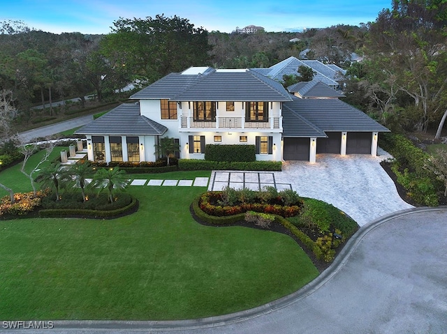 view of front facade featuring a garage, a front yard, and a balcony