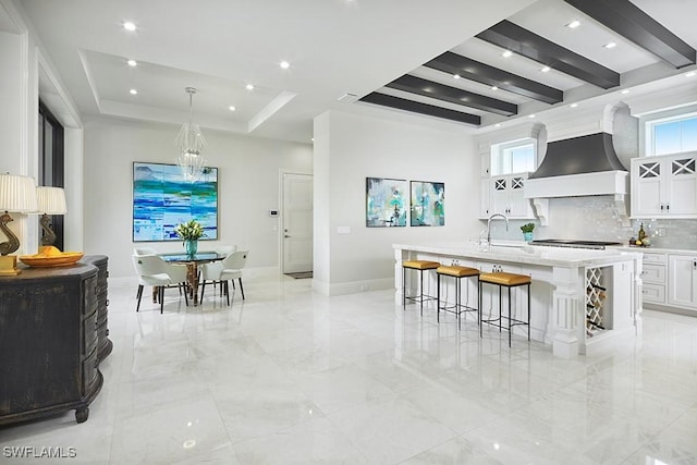 803 Shadow Lake Ln, Naples, FL 34108 - kitchen featuring custom exhaust hood, white cabinetry, light countertops, backsplash, and a raised ceiling