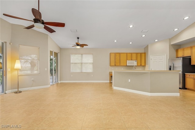 kitchen with vaulted ceiling, an island with sink, light tile patterned floors, ceiling fan, and stainless steel refrigerator with ice dispenser