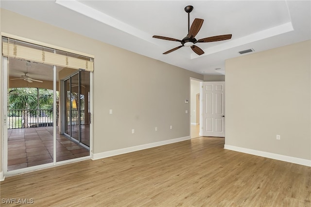 spare room with ceiling fan, a raised ceiling, and wood-type flooring