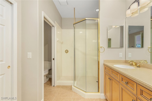 bathroom with a shower with door, toilet, vanity, and tile patterned floors