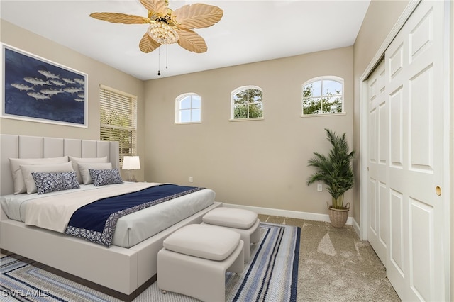 bedroom featuring a closet, multiple windows, light colored carpet, and ceiling fan